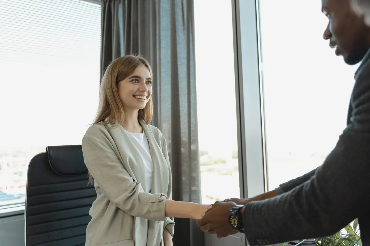 A smiling candidate shaking hands in an office