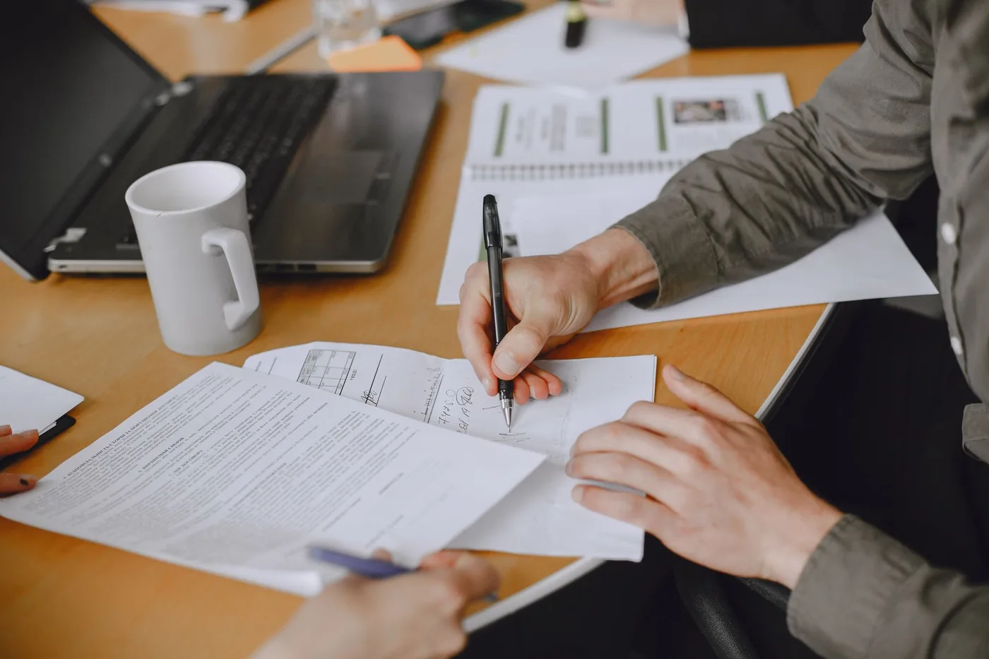 Hands signing documents at a business meeting